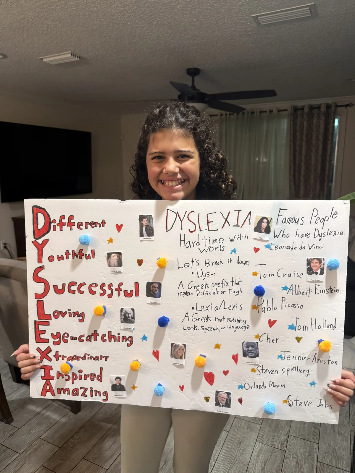 Tess smiling while holding her handmade Dyslexia Awareness Month poster