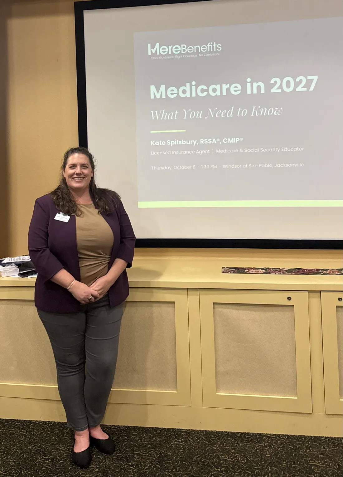 Kate Spilsbury standing beside the Medicare in 2027 title slide