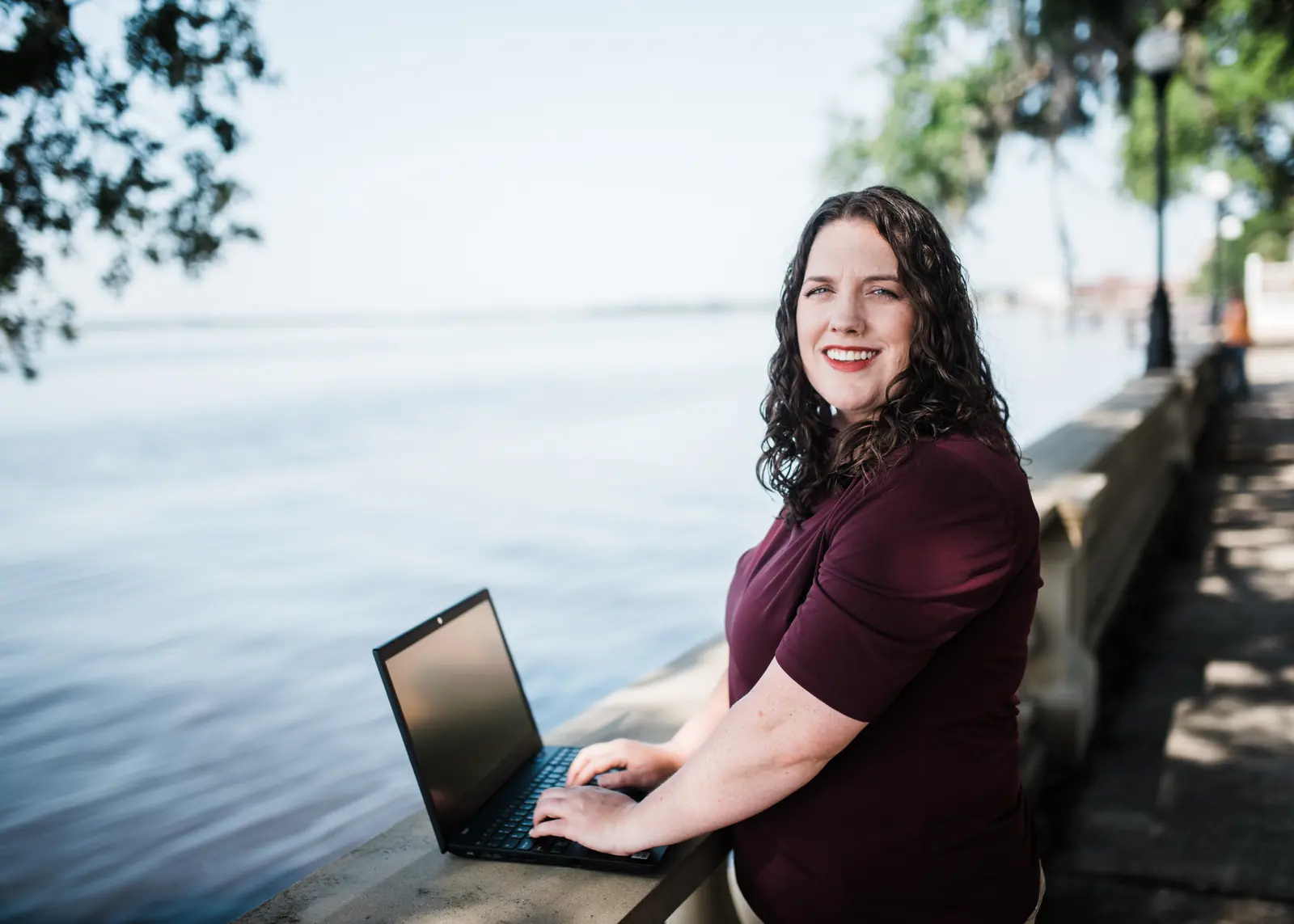 Kate Spilsbury reviewing coverage details on her laptop by the river