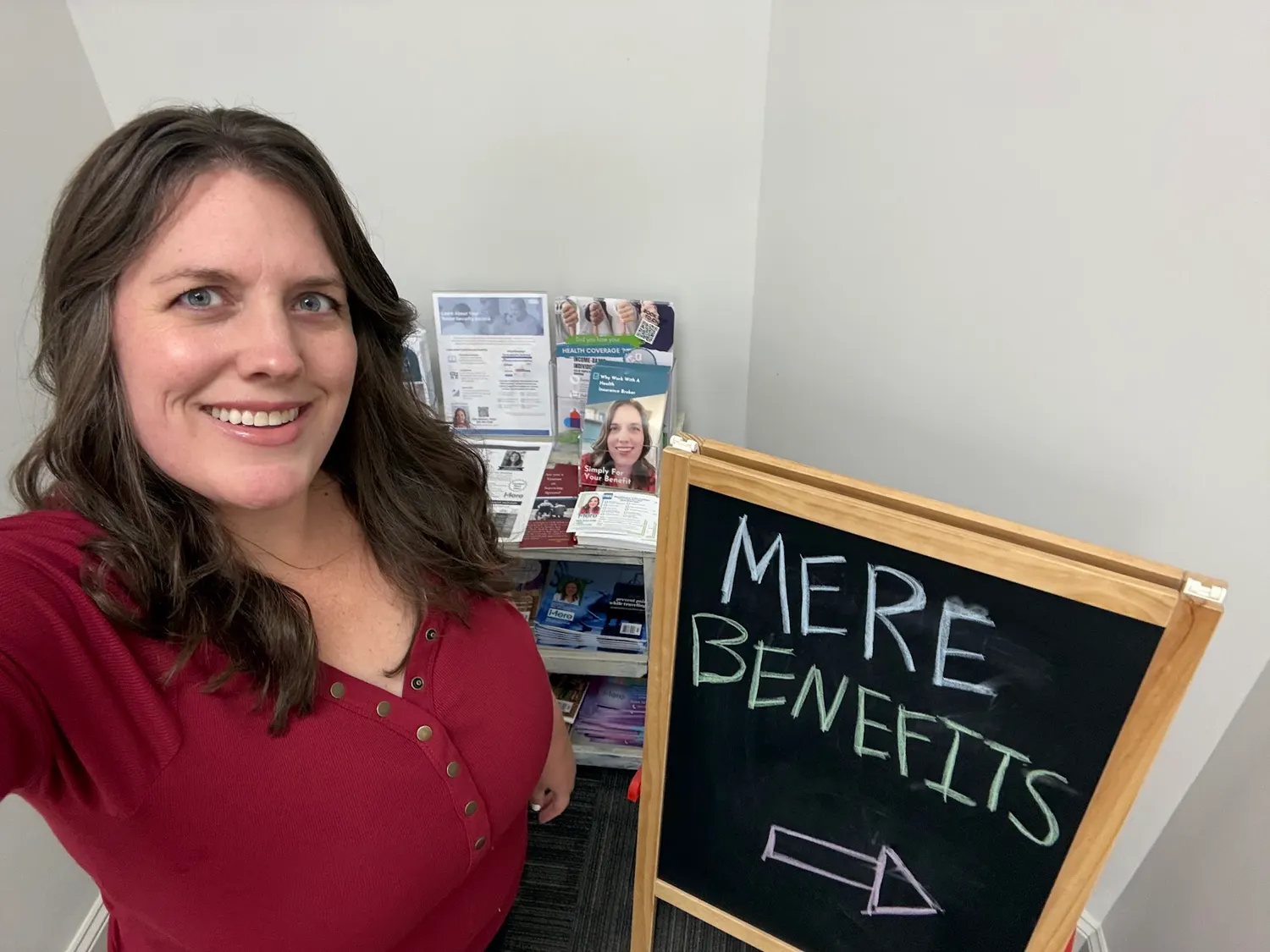 A chalkboard sign reading Mere Benefits with an arrow pointing to the office