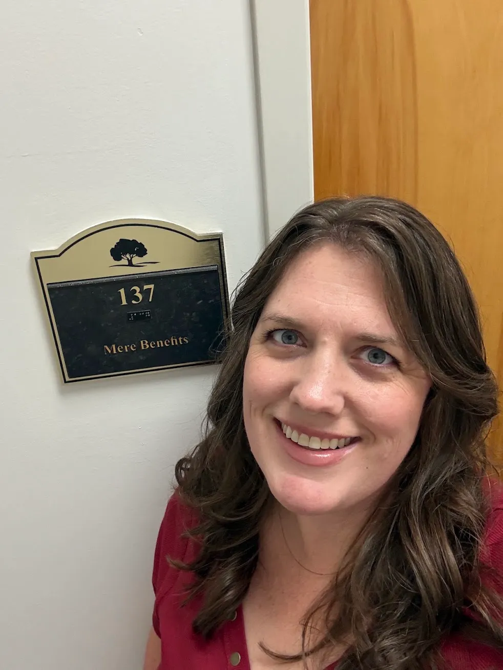 Kate Spilsbury beside the Mere Benefits sign at suite 137