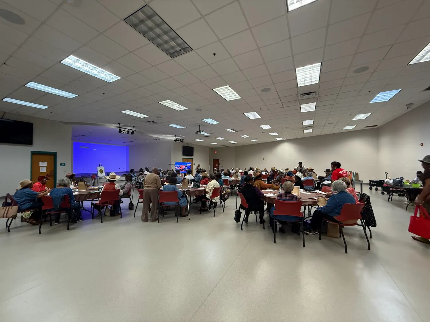 A community hall filled with attendees at a Mere Benefits outreach event