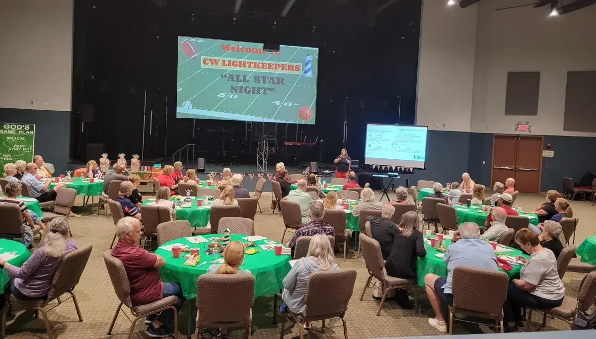 Kate Spilsbury presenting Medicare slides to a full banquet hall at a community All Star Night event